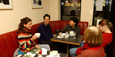 Foto: Eine gemütliche Runde im Caf&egrave; MaxB. Die Runde wirkt gemütlich. Das Gespräch ist angeregt. Draußen ist es schon dunkel – Feierabendverkehr. Niemand möchte schon los. 